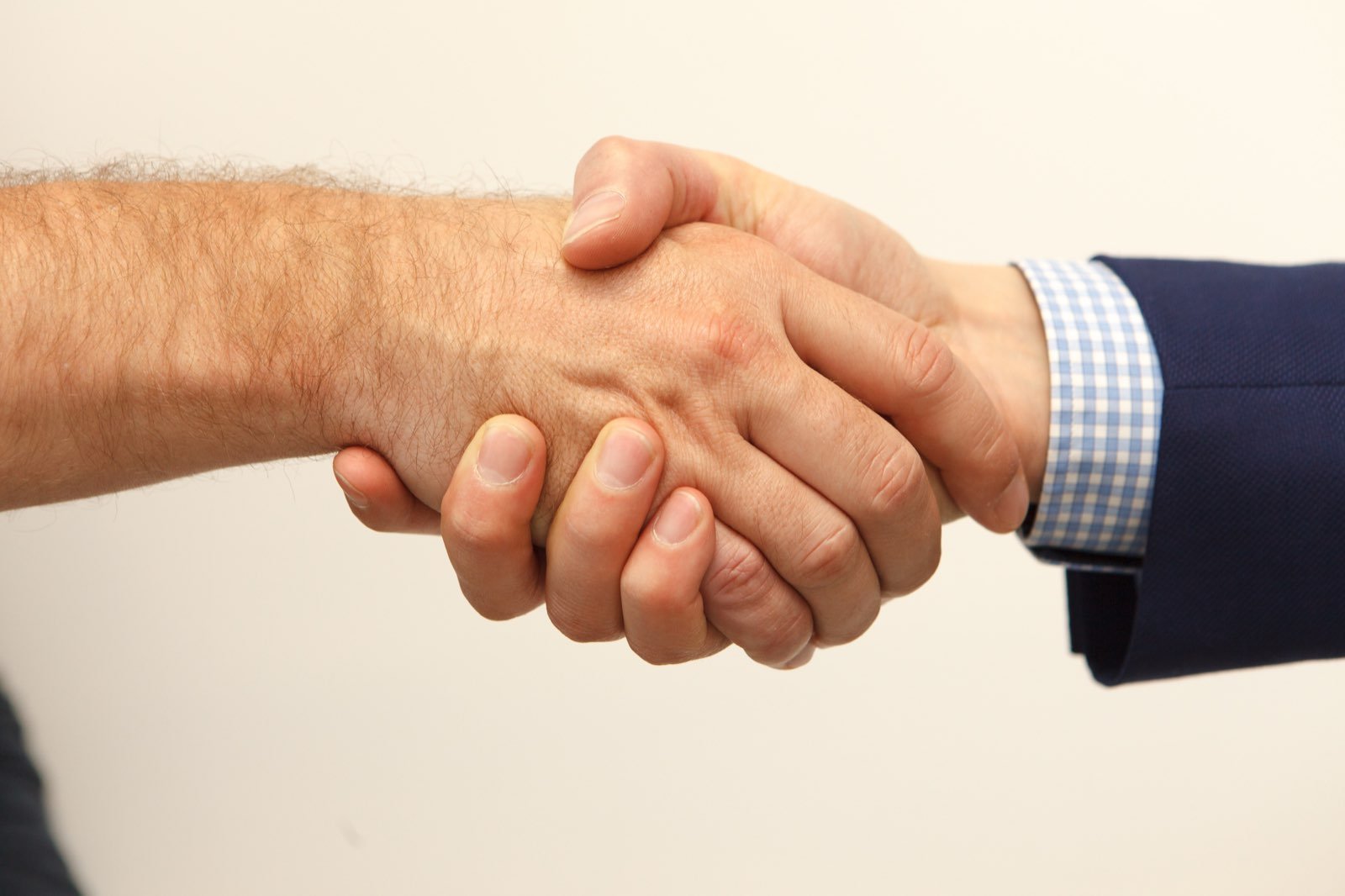 Two people shaking hands across a desk after agreeing on a project